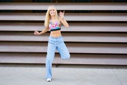 Smiling woman dancing modern music in the street