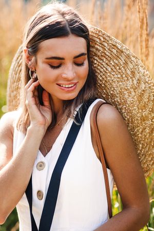 Wistful woman with straw hat on her back in a field