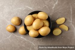 Top view of dark ceramic bowl overflowing with potatoes on marble counter bexKp4