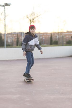 Teenager skateboarder riding on asphalt in playground