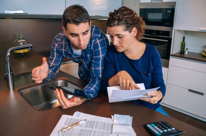 Couple having tense discussing about their monthly bills in kitchen