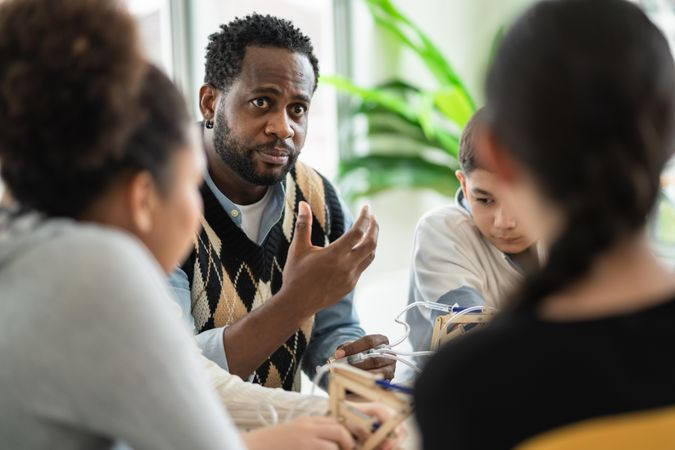 Black male teaching science equipment to young students