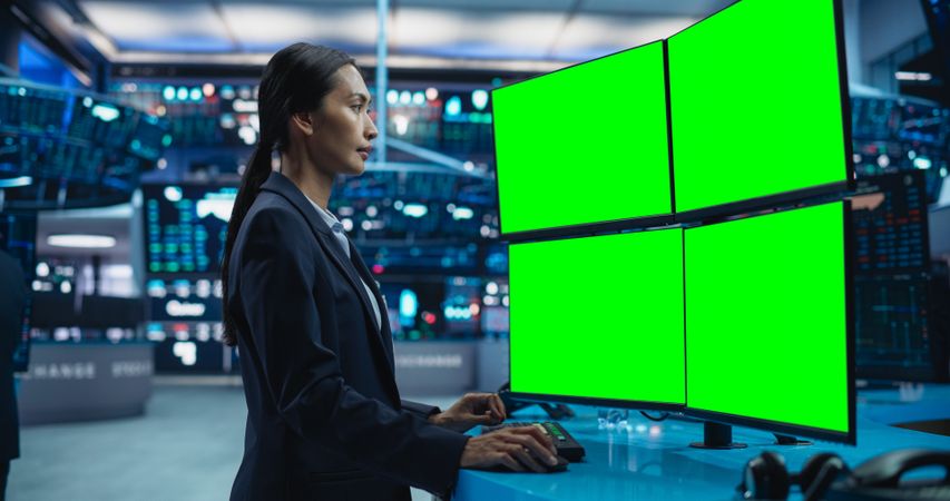 Young Female Stock Exchange Broker Working on a Computer with Multi-Screen Workstation With Green Screen Chromakey On Displays.
