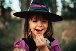 Laughing girl with teddy bear in witch costume