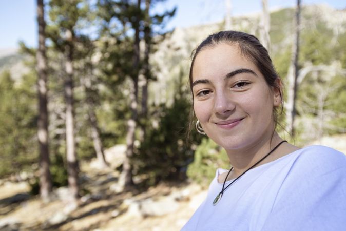 Young woman standing in the forest looking at camera