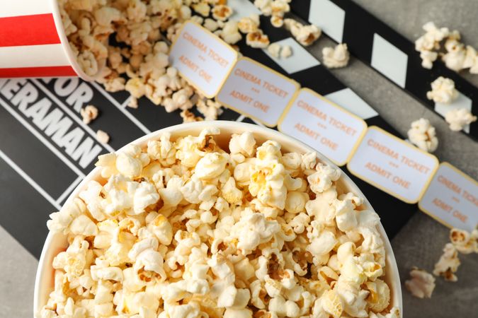 Clapperboard, tickets and buckets with popcorn on grey background, top view