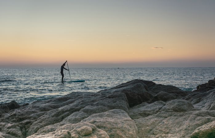 Man practicing paddle surfing with neoprene in a sunrise