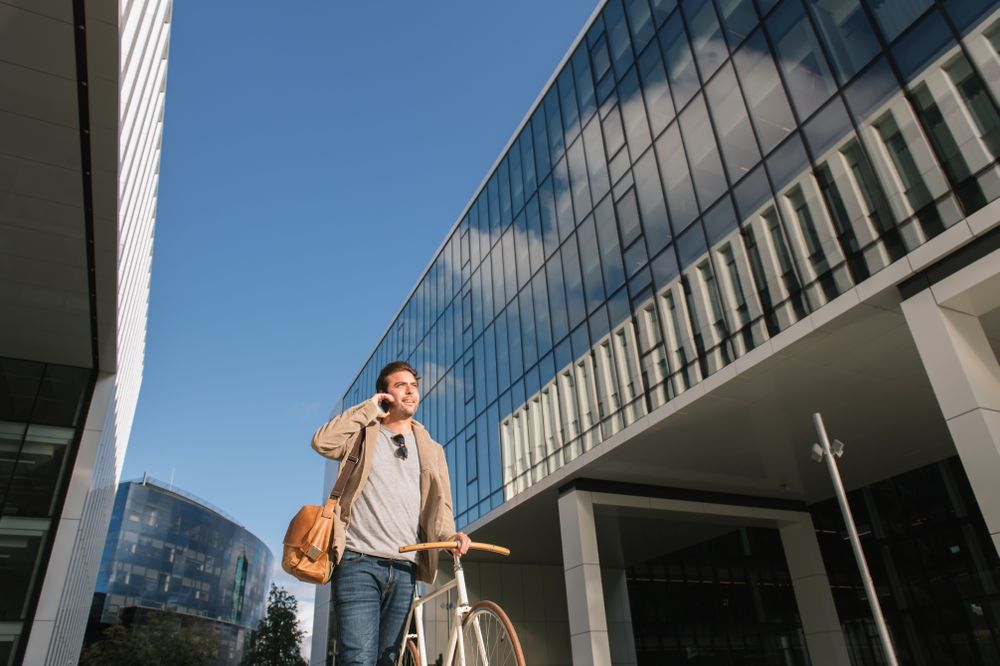 Man phoning while standing against modern building in downtown