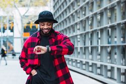 Stylish hurrying Black man walking near modern building