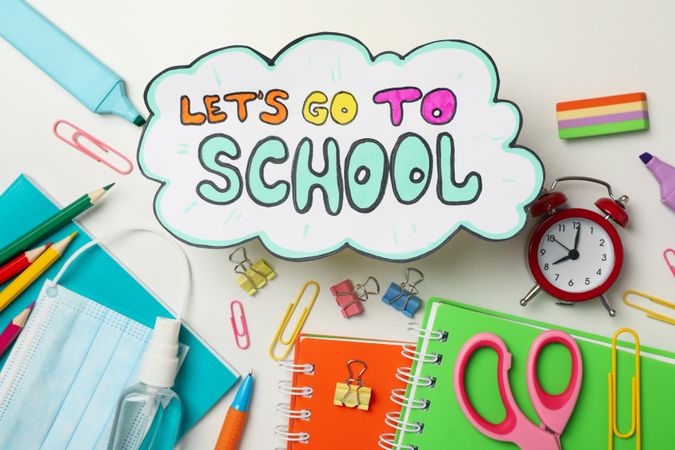 Text Let's go to school, school supplies, medical mask and sanitizer on blank background