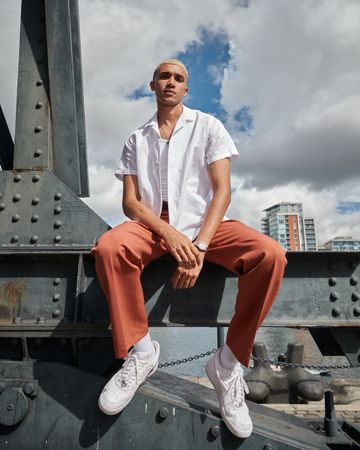 Stylish young man sitting on bridge