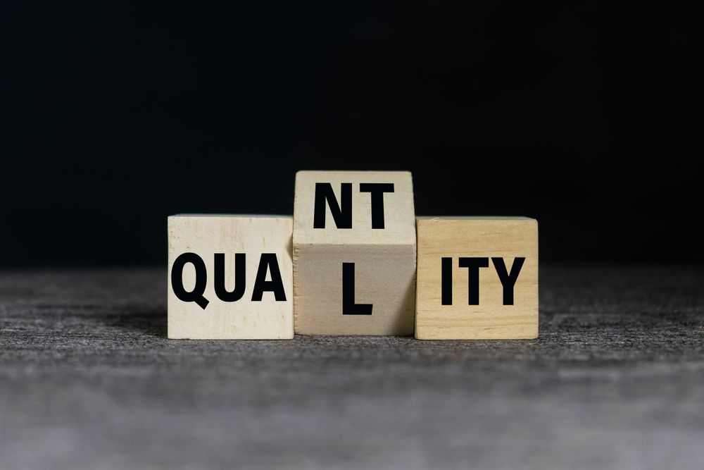 flip wooden blocks with quality and quantity words on dark background