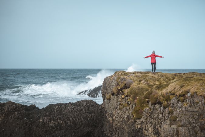 Woman on top of rock with sea surf