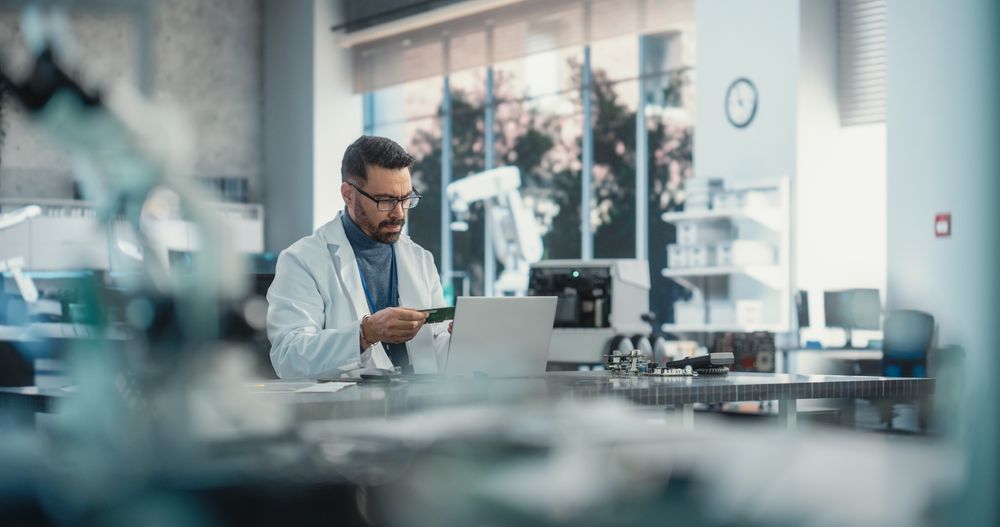 Portrait of a Professional Male Scientist Working in an Industrial Lab Using Laptop Computer.