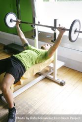 Man in green t-shirt lifting heavy bar exercising chest 5pA2j4