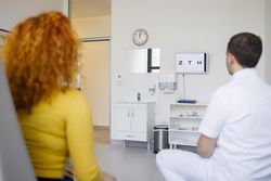 Red haired female reading eye chart with optometrist