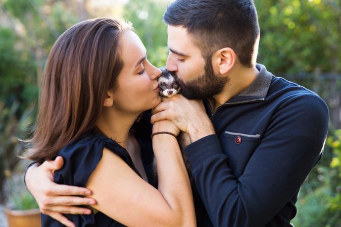 Man and woman kissing ferret outdoor