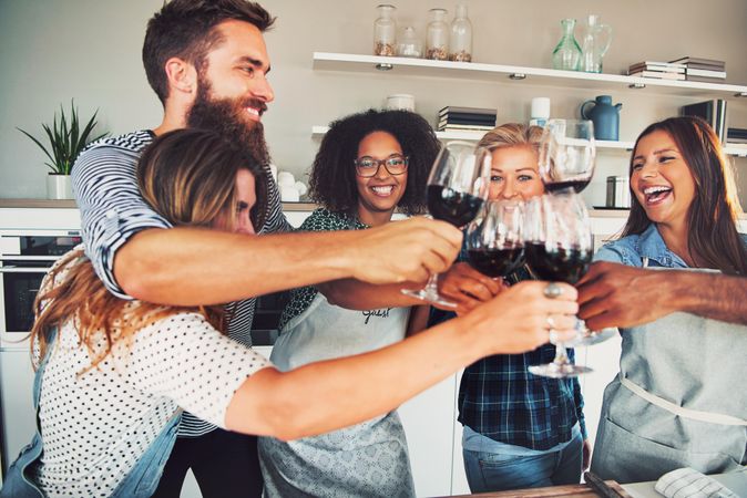 Multi-ethnic friends toasting with red wine at home