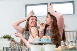 Mother and daughter playing in the kitchen with cupcakes