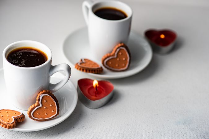 Two coffees with iced cookies and heart candles