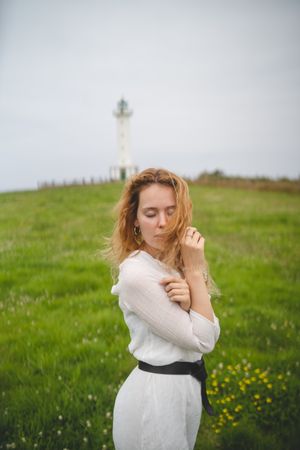 Tender woman in green field with lighthouse