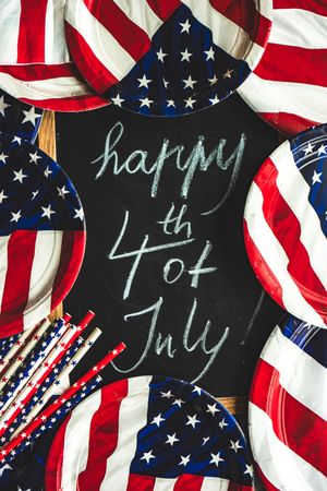 Chalkboard surrounded by USA flag tableware with the words "Happy 4th of July"