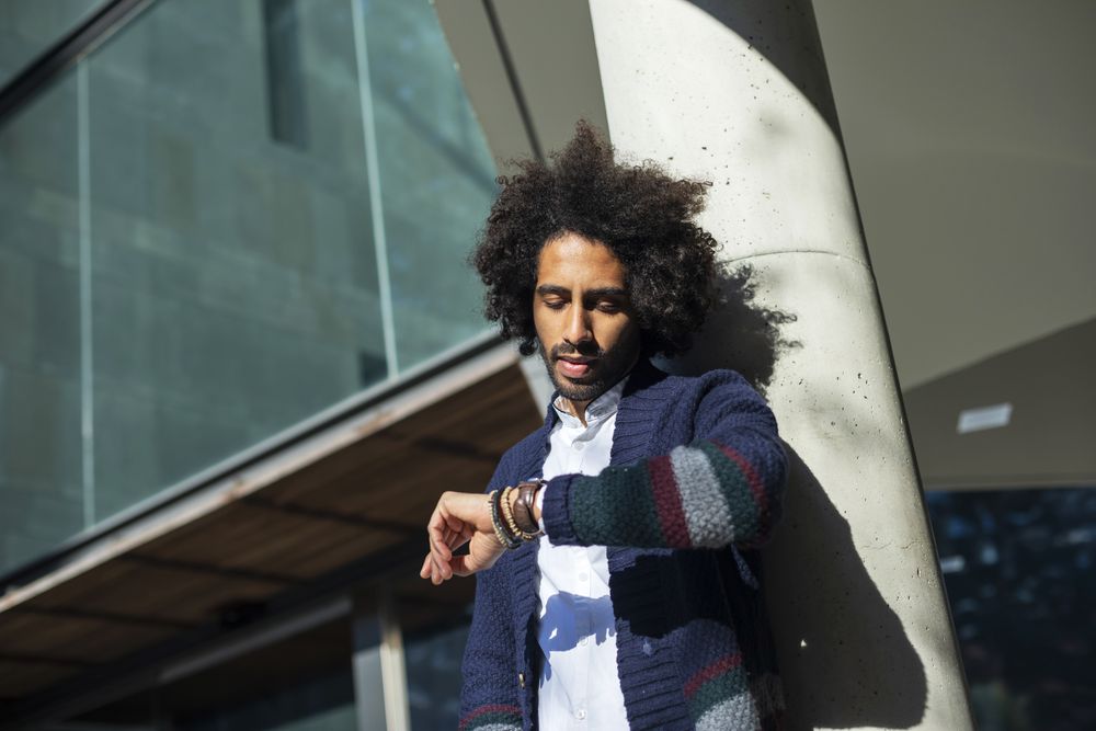 Black man checking watch outside on sunny day