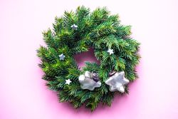 Christmas wreath with decorative stars on pink background
