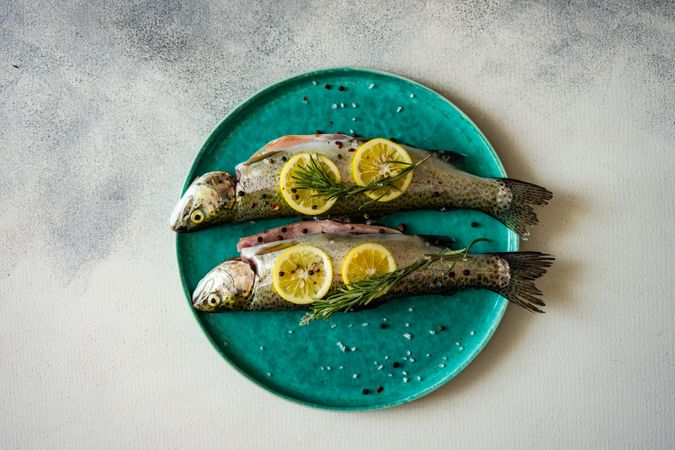 Top view of trout fish ready for cooking with lemon and rosemary