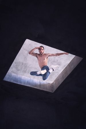 Young man jumping while practicing breakdance in shabby construction