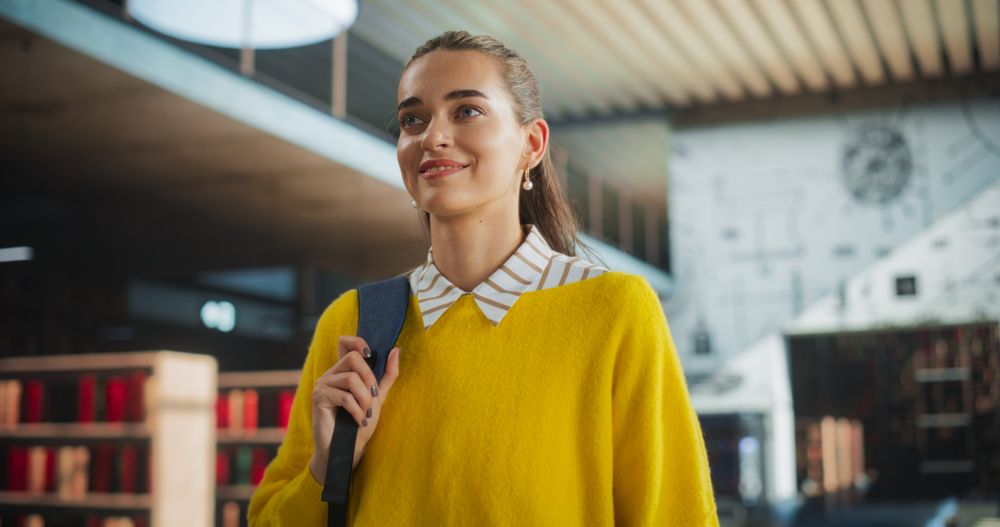 Portrait of a Young Female Walking Inside a Library Building with a Backpack. Multiethnic Woman Walking in College, Office Building, Shopping Center with Bookshop