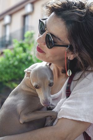 Woman kissing greyhound while relaxing on street