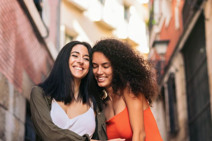 two young women going down street stairs smiling holding her hands and hugging