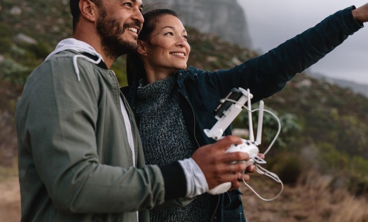 Man and woman flying drone outdoors in countryside