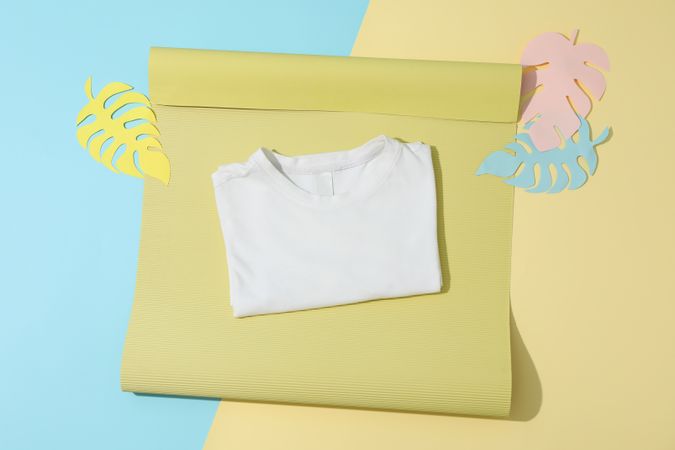 Folded t-shirt on color decorated background, space for text