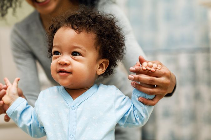 Toddler boy standing up with mother’s help