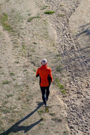 Looking down at rear of male jogging in the park, vertical