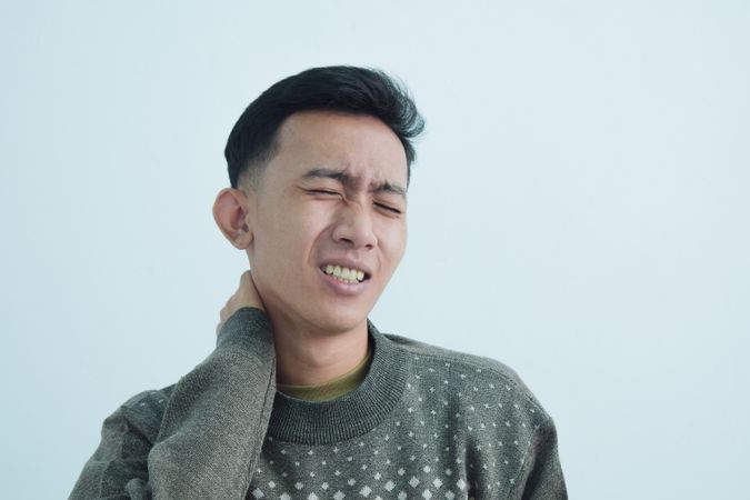 Asian young man touching neck in pain