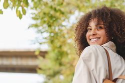 Smiling Black woman with curly hair in park