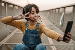 Funny girl taking selfie on smartphone on walkway