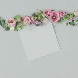 Line of pink flowers and leaves on marble background with paper card
