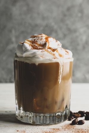 Glass of ice coffee with poured cream on wooden table