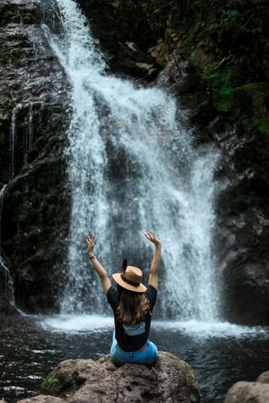 Smiling woman sitting near waterfall