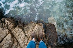 Person in leather boots on rocks near the coast