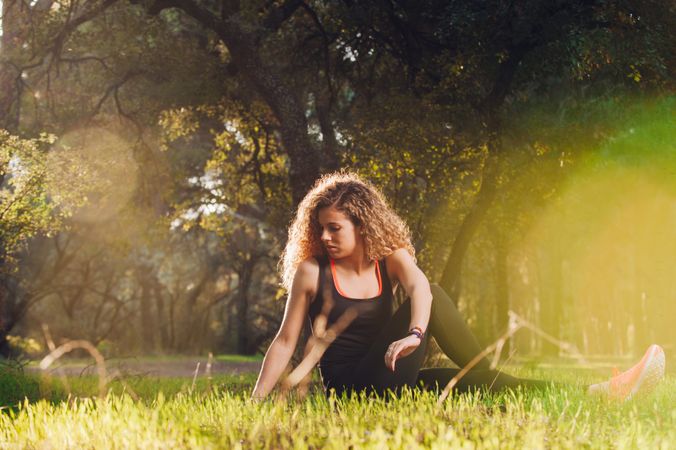 Happy woman stretching on sunny meadow