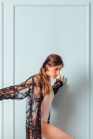 Graceful stylish woman in lace leaning on wall