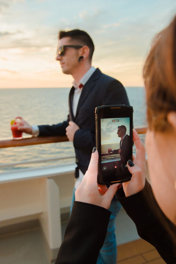 Woman taking photo of man on deck of ship at sea