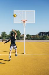 Young man playing on basketball court outdoor.