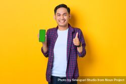 Asian man with thumbs up in plaid shirt holding smartphone with chroma key 0yDnjb