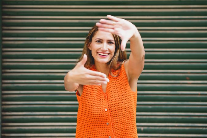 Portrait of woman smiling at camera framing her face with hands